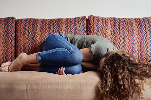 Mujer acostada en el sofá, que sufre de dolor abdominal photo