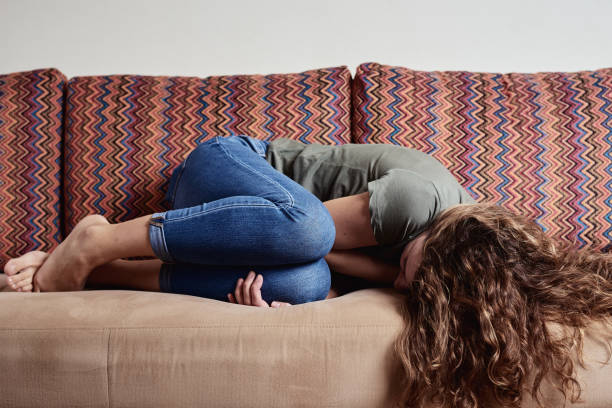 Woman lying on sofa, suffering from abdominal pain Woman at home suffering from abdominal pain, Exhausted person with depression chronic illness stock pictures, royalty-free photos & images