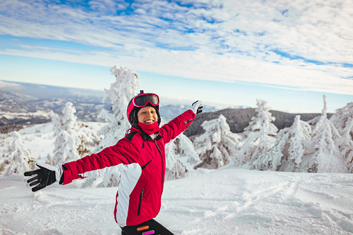 Beautiful outdoor portrait of young girl on the top of a ski mountain. With arms outstretched with joy.