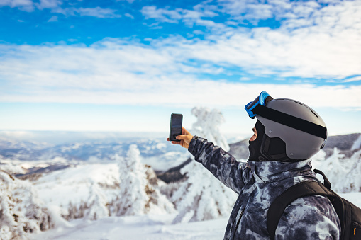 Men skier takes a photo of nature, enjoying the winter snowy mountain landscape.