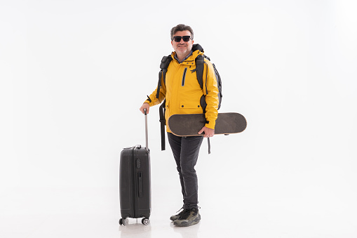 Cheerful traveler man with backpack and suitcase on white background