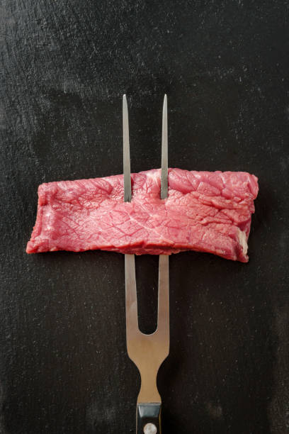 istock A piece of meat on a barbecue fork close-up. Fork with meat on a dark background. 1373280225