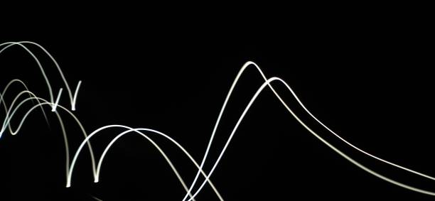 istock Closeup of White neon Curved Wave pattern abstract flowing in a isolated black background with copy space made using  photography technique called Long exposure. 1373281766