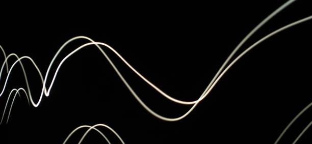 istock Closeup of White neon Curved Wave pattern abstract flowing in a isolated black background with copy space made using  photography technique called Long exposure. 1373281779