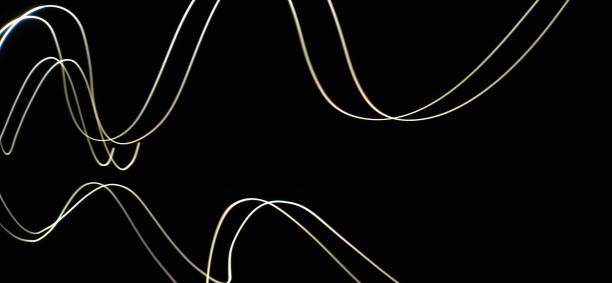 istock Closeup of White neon Curved Wave pattern abstract flowing in a isolated black background with copy space made using  photography technique called Long exposure. 1373281780