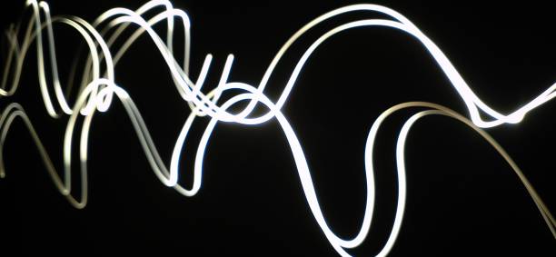 istock Closeup of White neon Curved Wave pattern abstract flowing in a isolated black background with copy space made using  photography technique called Long exposure. 1373281781