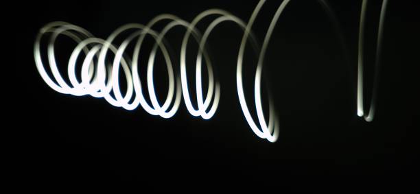 istock Closeup of White neon Curved Wave pattern abstract flowing in a isolated black background with copy space made using  photography technique called Long exposure. 1373281796