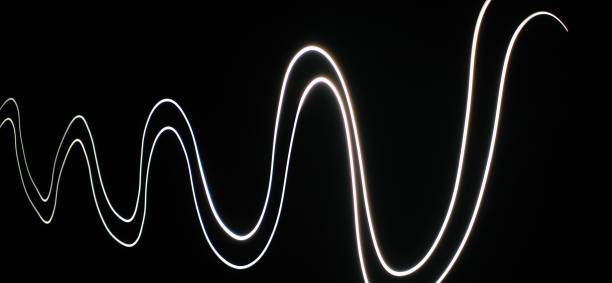 istock Closeup of White neon Curved Wave pattern abstract flowing in a isolated black background with copy space made using  photography technique called Long exposure. 1373281801