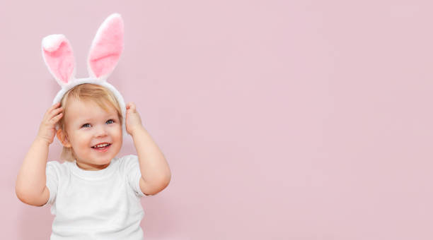 istock A cute little baby with rabbit ears on a pink background. 1373283208