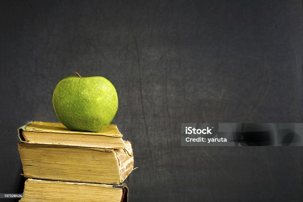 Mela verde sul libro di testo - Foto stock royalty-free di Colore nero