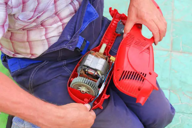 Man repairing an electric trimmer. Close-up. Background.