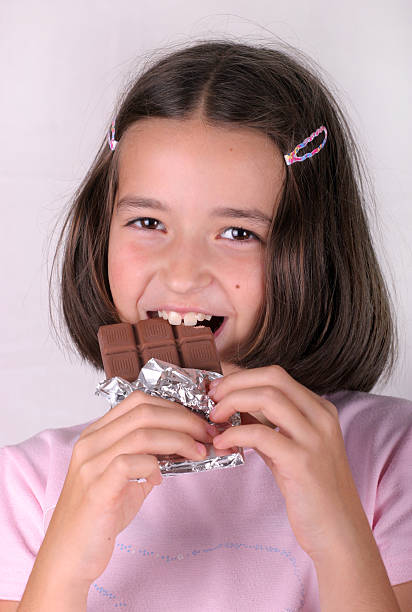 молодая девушка едят шоколадный бар - affectionate desire beauty brown стоковые фото и изображения