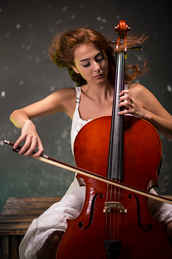 Red-haired girl in a white dress plays the cello.