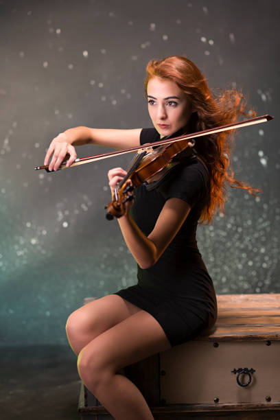 studio portrait of a violinist with long hair on a black background