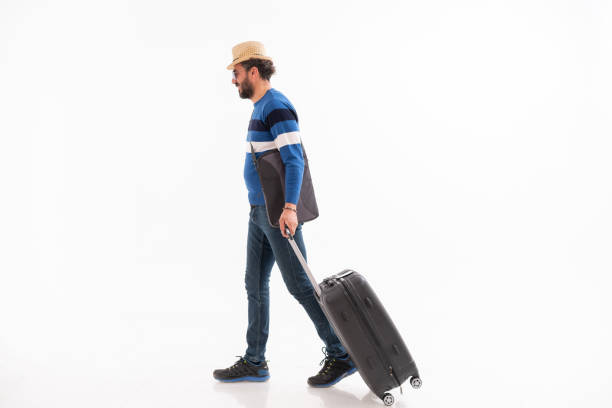 istock Traveler man with suitcase looking away and walking isolated on white. 1373295319