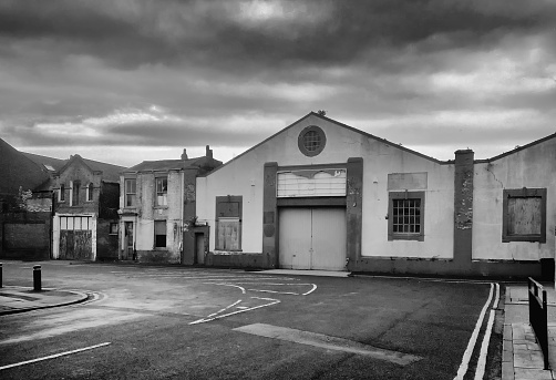 monochrome image of an empty street full of derelict abandoned building under a dark cloudy sky