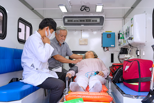 Doctor checkup patient in ambulance car. Along side with patient 's wife.  Before go to hospital. Medical and health care concept.