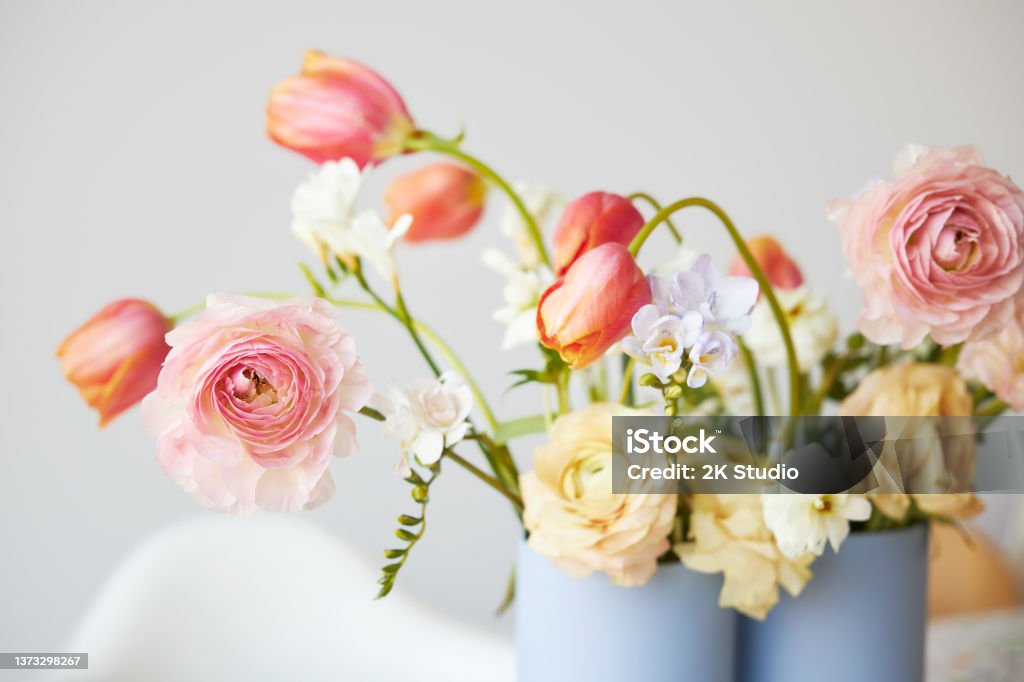 A modern spring bouquet of freesias, ranunculus and tulips in a beautiful vase A modern spring bouquet of freesias, ranunculus and tulips in a beautiful vase on a dining table Flower Stock Photo