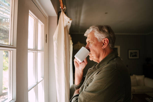 istock Caucasian senior male drinking coffee looking out window concerned 1373299236