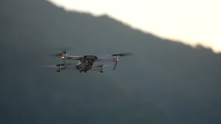 Drone quad copter with digital camera flying at sunset