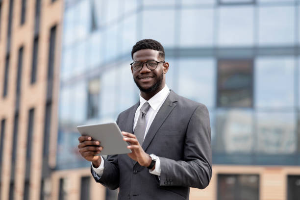 istock Positive african american entrepreneur using digital tablet during lunch break, walking near office center outdoors 1373299823