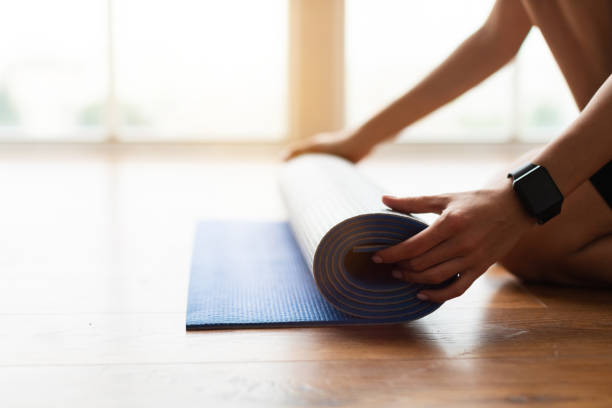 primo piano della giovane donna che srotola il tappetino da yoga sul pavimento - unrolling foto e immagini stock
