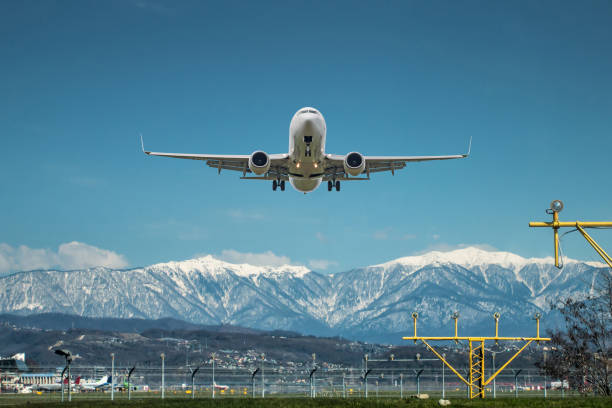 decollo di un aereo passeggeri bianco sullo sfondo di alte montagne pittoresche - airfield mountain snow airport foto e immagini stock