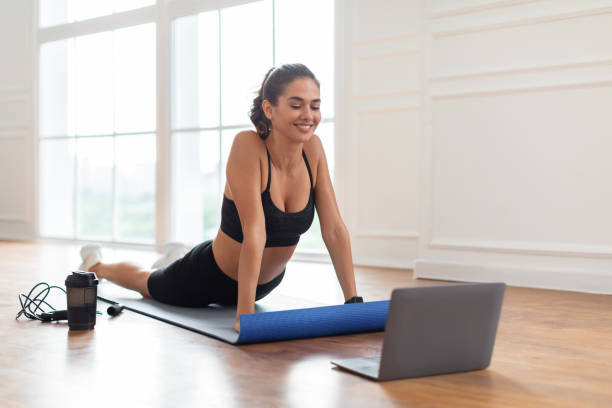 istock Young woman stretching back on mat with pc 1373299886
