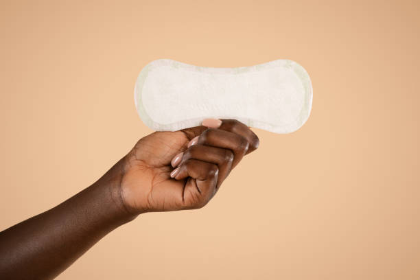 Unrecognizable black woman hand holding pad, closeup Unrecognizable african american woman hand holding daily pad, posing over beige studio background, isolated, cropped, copy space. Female period and intimate hygiene, menstrual products concept sanitary pad stock pictures, royalty-free photos & images