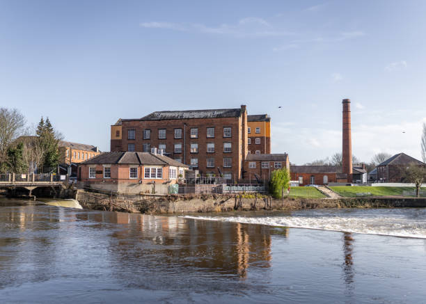 Mill on the river Derwent at Derby Abby. Mill on the river Derwent at Derby Abby. Fast flowing beautiful river and old mill warehouse with red brick chimney. derby city stock pictures, royalty-free photos & images