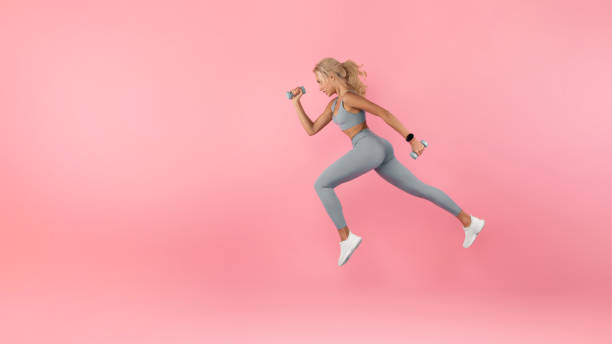 istock Young Woman Running With Dumbbells Isolated On Studio Background 1373301342