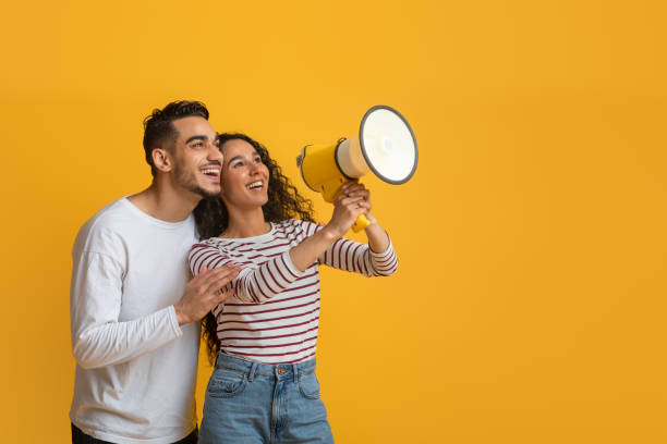 istock Nice Promo. Cheerful Arab Couple Using Megaphone For Making Announcement 1373302212