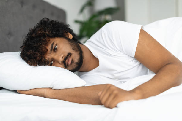 istock Sad indian guy in pajamas laying in bed 1373303092