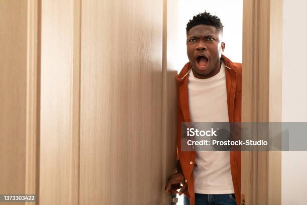 Shocked African American Man Opening The Door Standing At Home Stock Photo - Download Image Now