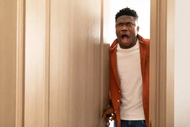 Photo of Shocked African American Man Opening The Door Standing At Home