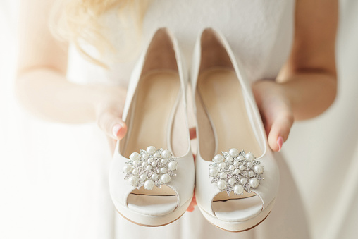 Bride holding wedding shoes