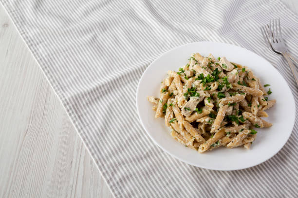 istock Homemade Chicken Alfredo Penne with Parsley on a white plate, side view. Copy space. 1373304382