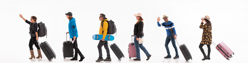 Group of travelers of different ethnicity and different ages walking with their suitcases on white background.