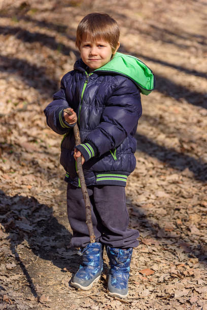 istock A boy is playing with a wooden stick in the woods 1373307882