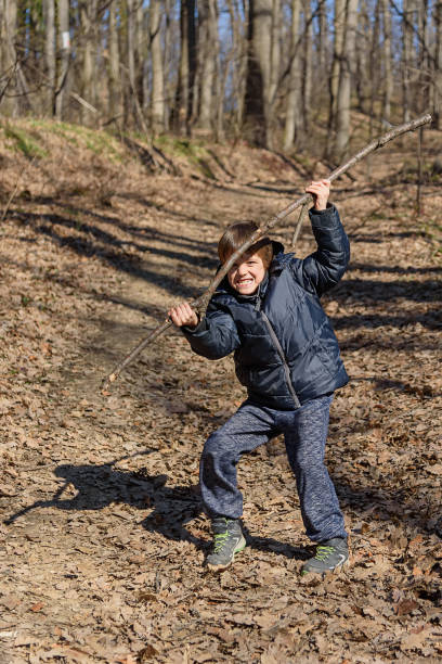 istock A boy is playing with a wooden stick in the woods 1373307883