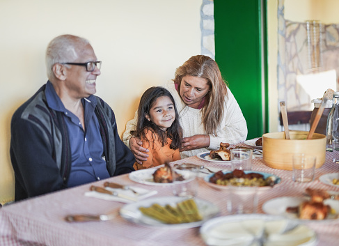Happy latin grandparents enjoy lunch with little granddaughter - Family love