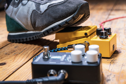 Close-up as a guitarist's foot activates an overdrive guitar effects pedal, with a reverb pedal in the foreground.