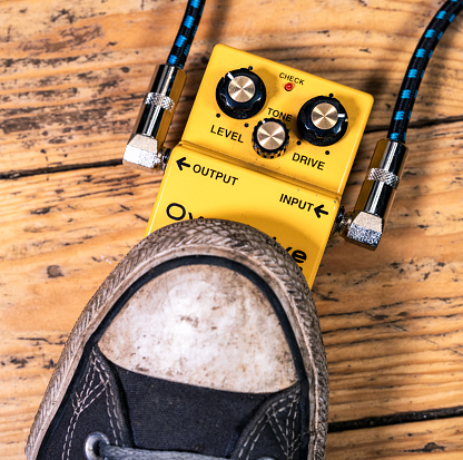 Close-up as a guitarist's foot activates an overdrive guitar effects pedal.