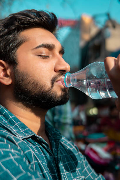 primer plano de un joven bebiendo agua de una botella. - sediento fotografías e imágenes de stock