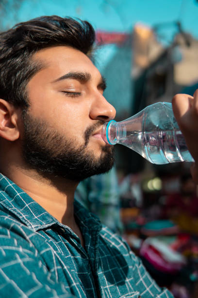 close-up of a young man drinking water from a bottle. - thirsty imagens e fotografias de stock