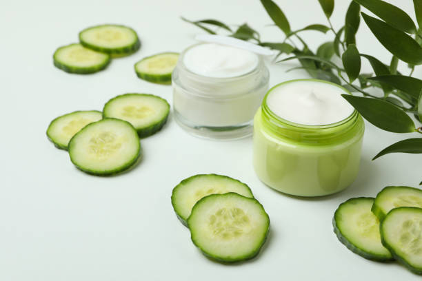 istock Jars with cosmetic cream, cucumber slices and branch on white table 1373313875