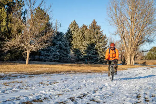 senior male cyclist riding a touring bike in winter on a trail covered by snow  in Fort Collins, Colorado