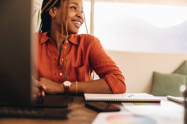 Female designer smiling in her office Female designer smiling while sitting in front of her computer. Happy young graphic designer drawing on a digital tablet with a stylus pen. Creative young woman working in her home office. small office stock pictures, royalty-free photos & images