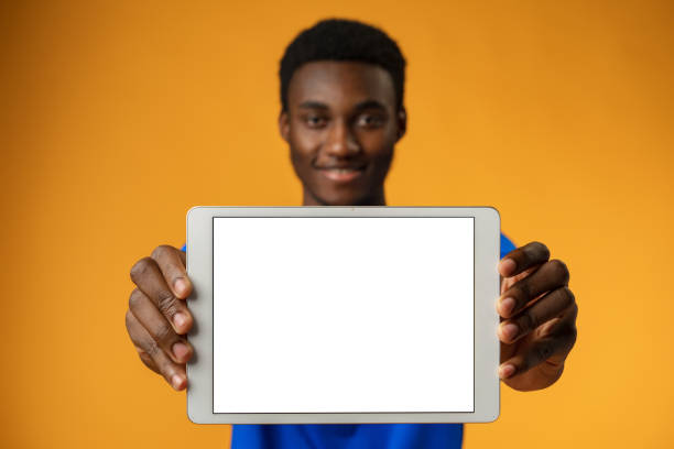 istock African american man showing blank digital tablet screen with copy space in yellow studio. 1373346700