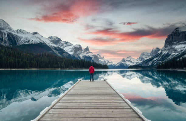 Spirit Island with male traveler enjoying on pier at the sunset in Maligne lake, Jasper national park Scenery of Spirit Island with male traveler enjoying on pier at the sunset in Maligne lake, Jasper national park, Canada travel stock pictures, royalty-free photos & images